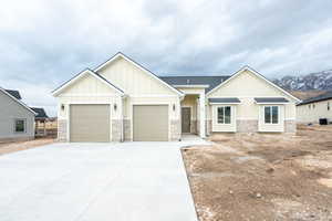 Craftsman inspired home featuring board and batten siding, concrete driveway, an attached garage, stone siding, and roof with shingles