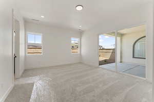 Unfurnished bedroom featuring light carpet, access to exterior, and recessed lighting