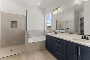Bathroom with walk in shower, a garden tub, double vanity, light wood-style flooring, and a spacious closet