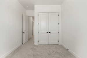 Unfurnished bedroom with light carpet and a closet
