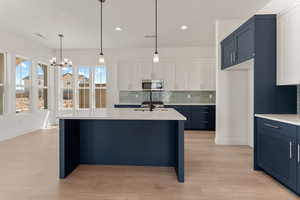 Kitchen featuring decorative backsplash, decorative light fixtures, an island with sink, and recessed lighting