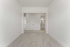 Hallway with light carpet and baseboards