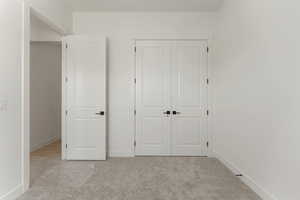 Unfurnished bedroom featuring light carpet and a closet