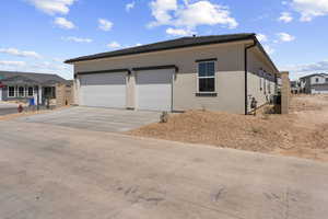 View of front of home featuring driveway, stucco siding, and a garage
