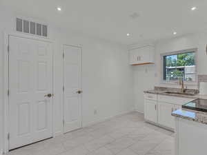 Kitchen with white cabinets, light stone countertops, recessed lighting, and range with electric cooktop