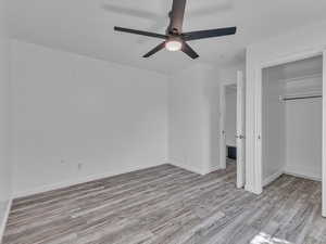 Unfurnished bedroom featuring light wood-style floors, a ceiling fan, and a walk in closet