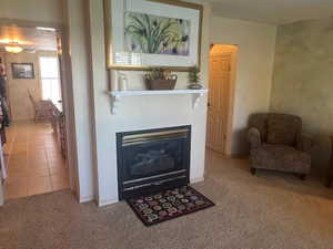 Living room featuring a glass covered fireplace, light colored carpet, and light tile patterned flooring