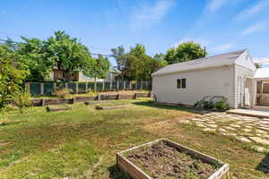 View of yard featuring a vegetable garden, a patio, a detached garage, and an outdoor structure