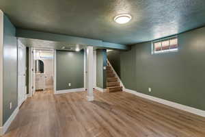 Below grade area featuring a textured ceiling, wood finished floors, and stairs