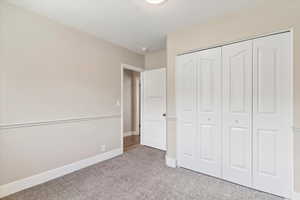 Unfurnished bedroom with light colored carpet and a closet