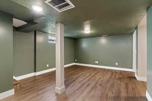 Below grade area with a textured ceiling and wood finished floors