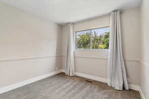 Empty room featuring light colored carpet and baseboards
