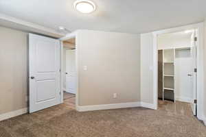 Unfurnished bedroom with a textured ceiling, carpet flooring, and a spacious closet
