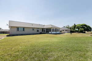 Rear view of house with a sunroom and a yard