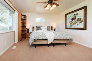Bedroom with light colored carpet and a ceiling fan