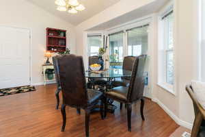 Dining space with wood finished floors, lofted ceiling, and a chandelier