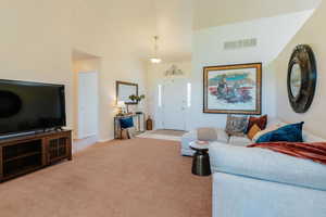 Living room featuring light colored carpet and a high ceiling