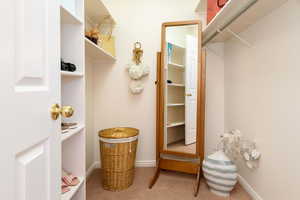 Primary Walk in closet with light colored carpet