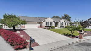Ranch-style house with concrete driveway, an attached garage, stucco siding, and a front yard