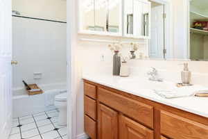 Bathroom featuring vanity, bathtub / shower combination, light tile patterned floors, and a closet