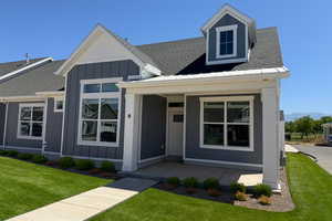 View of front of house with a shingled roof, a front lawn, and board and batten siding