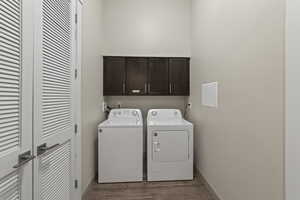 Laundry room with cabinet space, independent washer and dryer, and wood finished floors