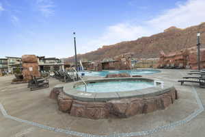 Community pool featuring a hot tub, a patio, and a mountain view