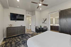 Bedroom featuring a barn door, ceiling fan, recessed lighting, and ensuite bath