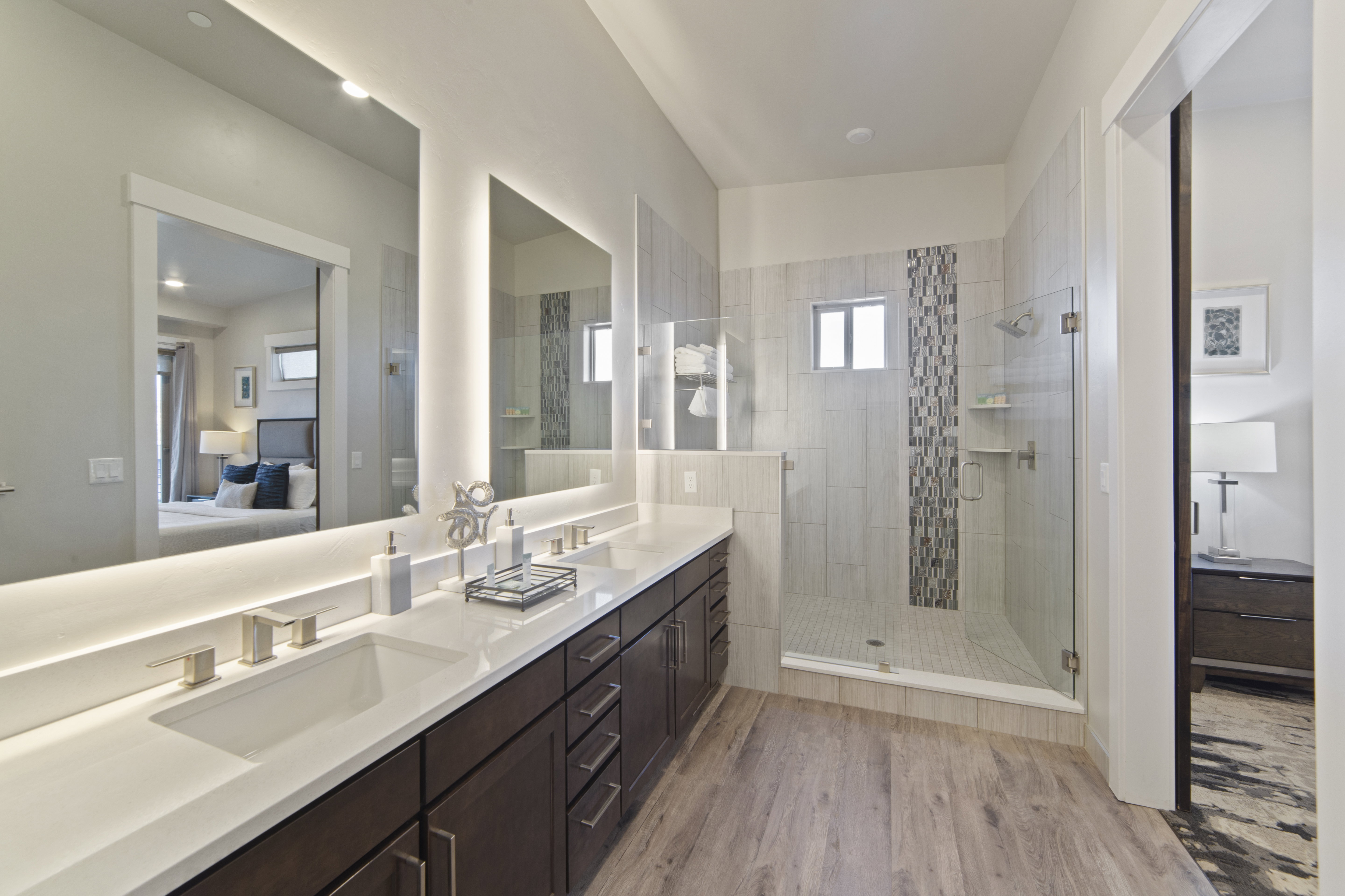 Ensuite bathroom featuring light wood-type flooring, double vanity, and a shower stall