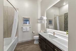 Bathroom with shower / bath combo with shower curtain, light wood-style floors, and vanity