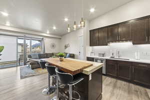 Kitchen with butcher block countertops, a breakfast bar area, dark brown cabinets, open floor plan, and pendant lighting