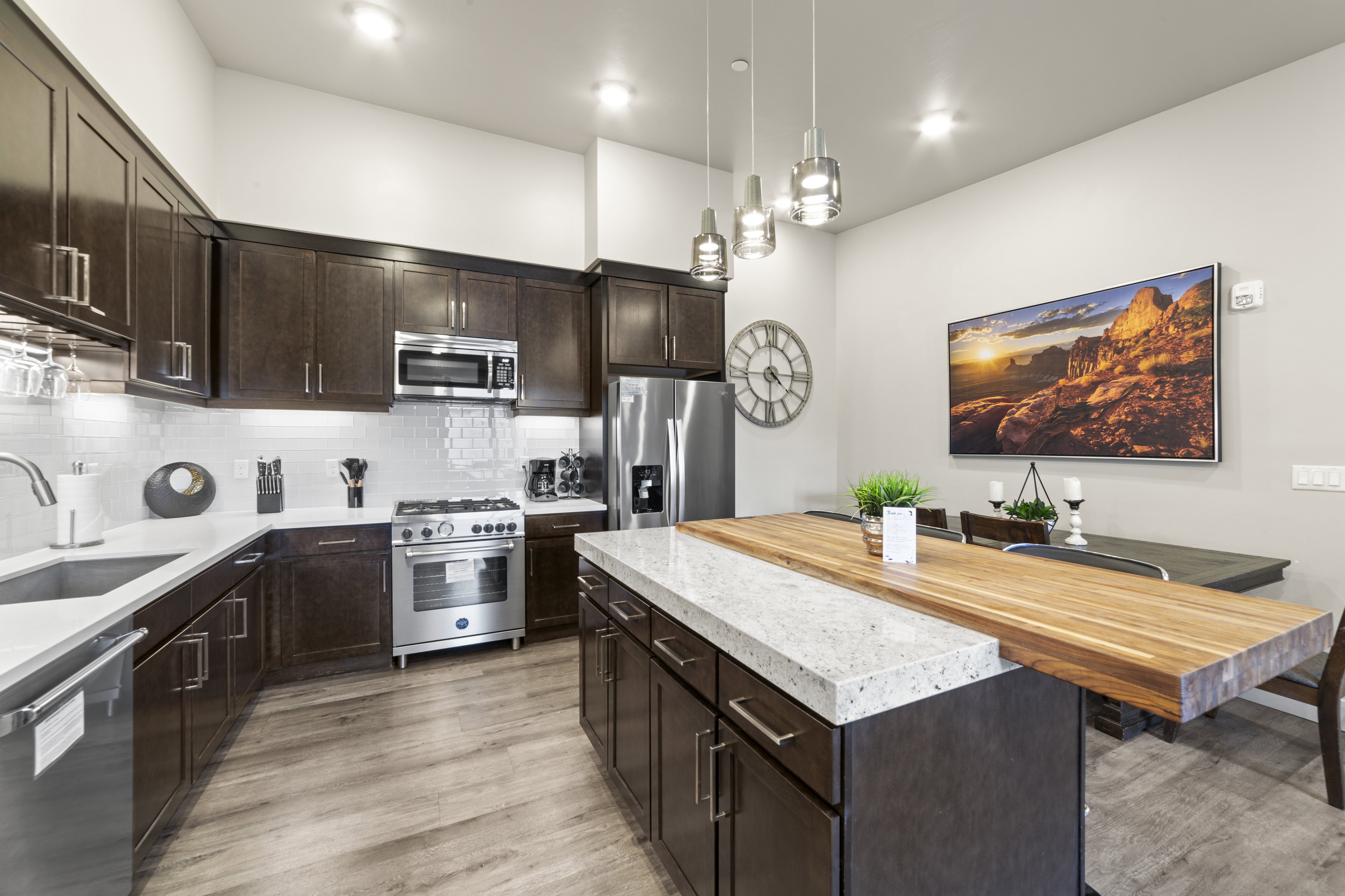 Kitchen featuring dark brown cabinetry, stainless steel appliances, a center island, tasteful backsplash, and pendant lighting