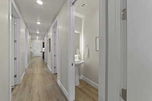 Hallway with light wood-type flooring and recessed lighting