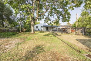 Rear view of house with a fenced backyard and a patio