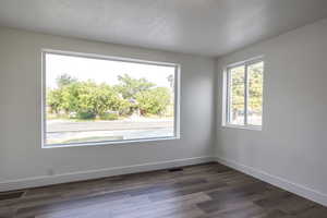 Empty room featuring a textured ceiling and dark wood-style flooring