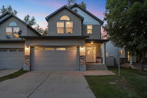 View of front facade featuring stone siding, driveway, a porch, and a front lawn