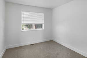 Empty room featuring light colored carpet and baseboards