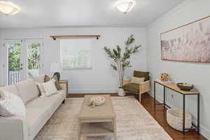 Living room with wood finished floors, crown molding, and french doors