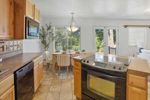 Kitchen with black appliances, pendant lighting, tasteful backsplash, crown molding, and french doors