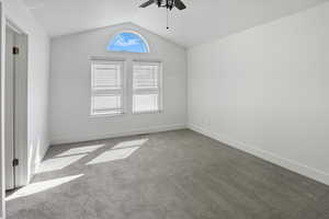 Empty room featuring carpet floors, lofted ceiling, and ceiling fan