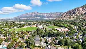 Aerial view of property and surrounding area featuring nearby suburban area and a mountainous background