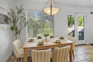 Dining room featuring light tile patterned floors, plenty of natural light, french doors, and crown molding