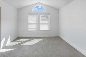 Carpeted empty room with lofted ceiling and baseboards