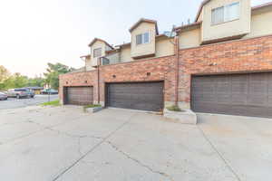 Rear view of house with concrete driveway, brick siding, and an attached garage
