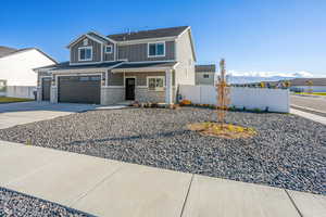 View of front of property featuring board and batten siding, concrete driveway, a garage, brick siding, and a porch
