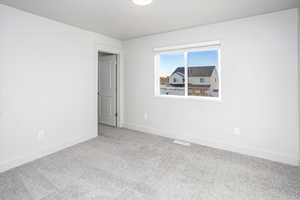 Unfurnished room featuring baseboards and light carpet