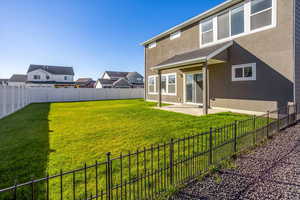 Back of house with stucco siding, a fenced backyard, a patio, and a residential view