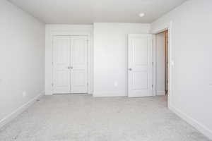 Unfurnished bedroom featuring light colored carpet and a closet