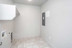 Laundry area featuring light tile patterned floors, hookup for a washing machine, electric panel, and hookup for an electric dryer