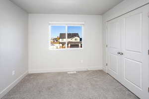 Unfurnished bedroom with light colored carpet and a closet